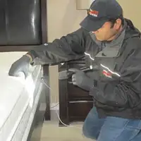Bed bug inspection technician checking a mattress and bed frame for signs of infestation in Riverside, CA