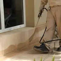 General pest control technician spraying exterior perimeter around a home in Riverside, CA