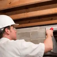 Termite inspection technician checking a basement wall and framing for termite activity in Riverside, CA
